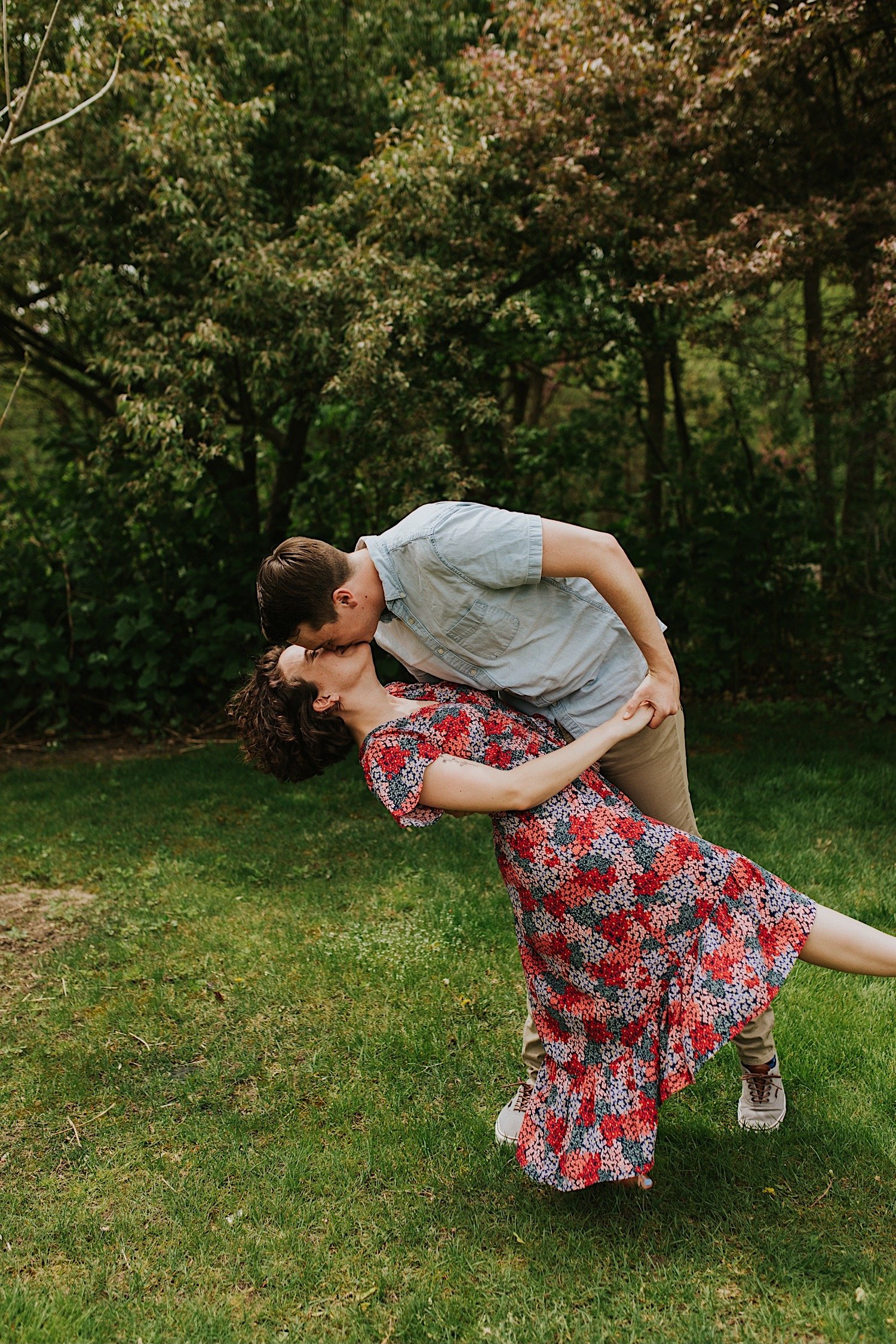 A fiancé dips his fiancee during their engagement session at a park in Downtown Normal Illinois