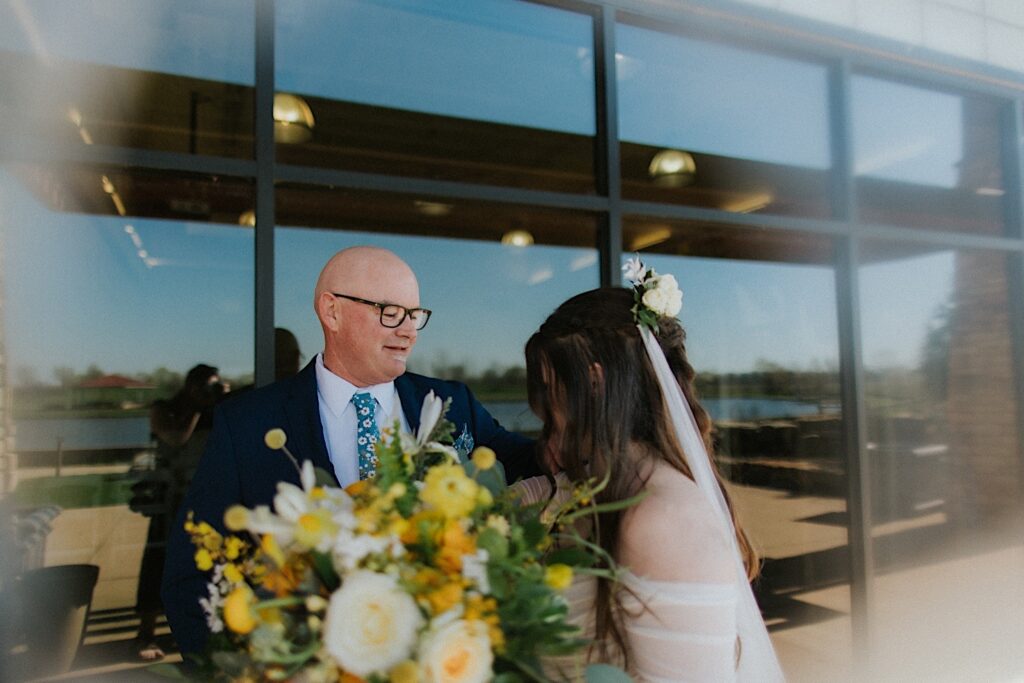 A father reaches out to hug his daughter in front of Erin's Pavilion after seeing her in her wedding dress for the first time