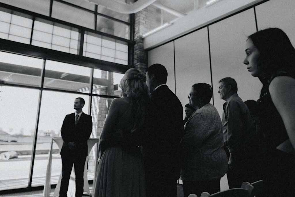 Black and white photo of guests of a wedding at Erin's Pavilion standing during the wedding ceremony