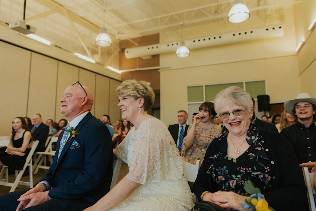 Guests of an indoor wedding reception at Erin's Pavilion smile and laugh during the vow reading