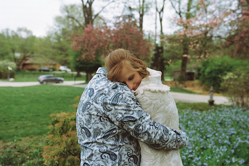Film photo of a bride being hugged by a groom in their front yard
