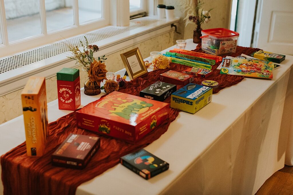 A table set up with different board game boxes as well as bubbles and other toys to entertain kids at a wedding reception