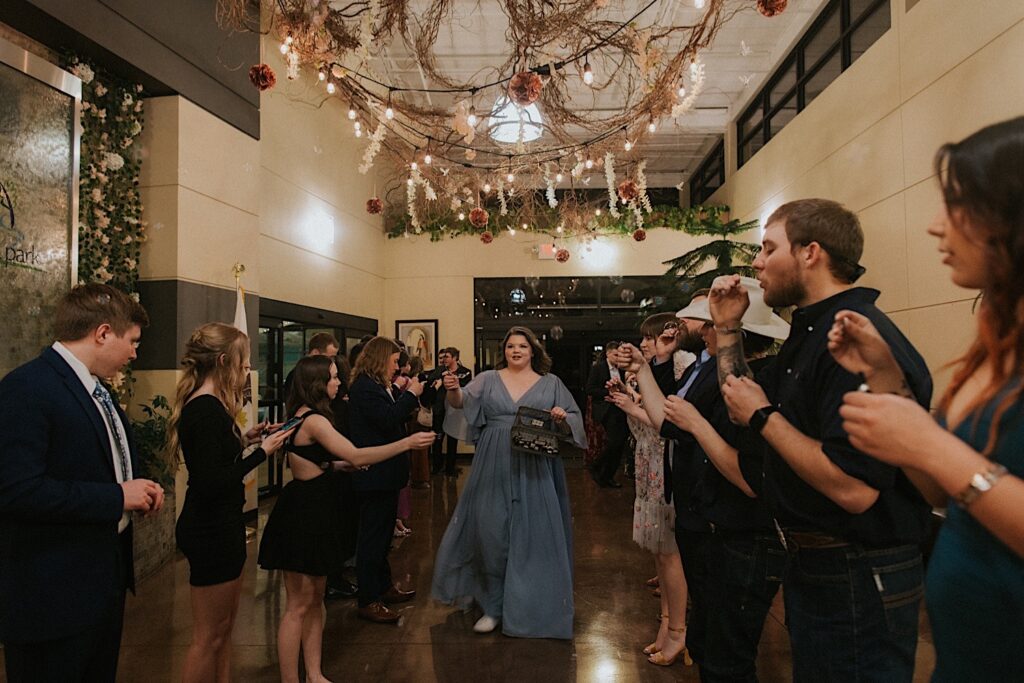 A woman hands out bubble blowers and bubble liquid to guests lining the exit hall at Erin's Pavilion waiting for the bride and groom to exit