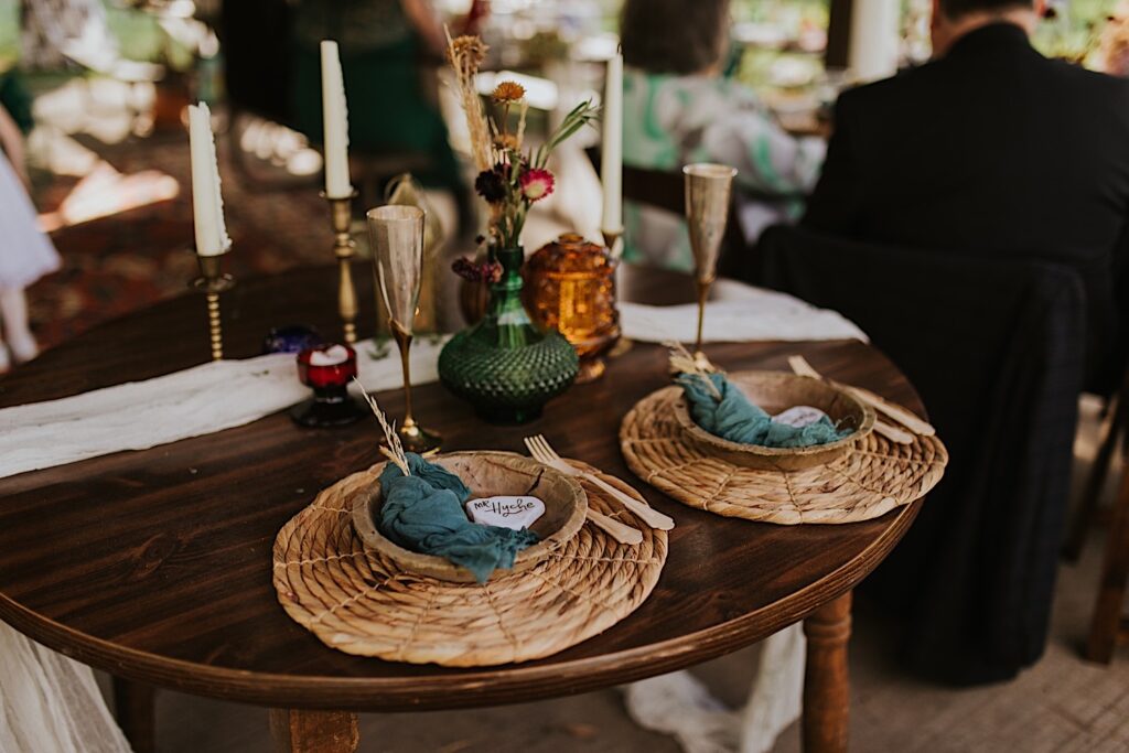 A table is set up for a backyard wedding with compostable plates and silverware