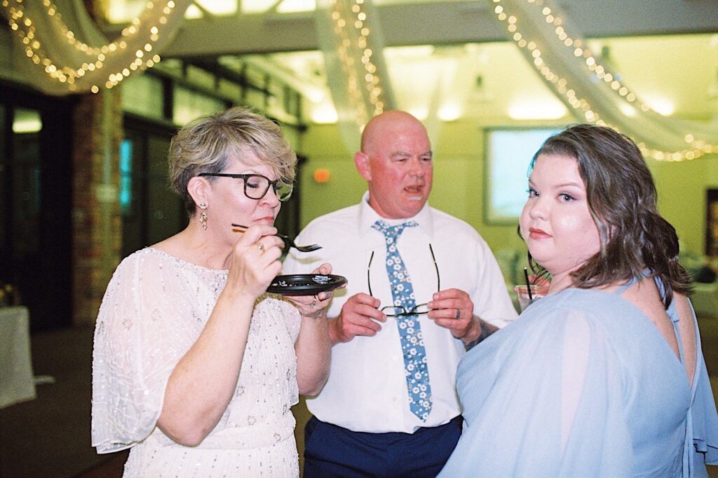 Film photo of three guests of a wedding reception mingling with one another