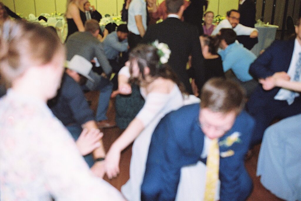 Film photo  of a bride and groom dancing with the guests of their wedding during their reception