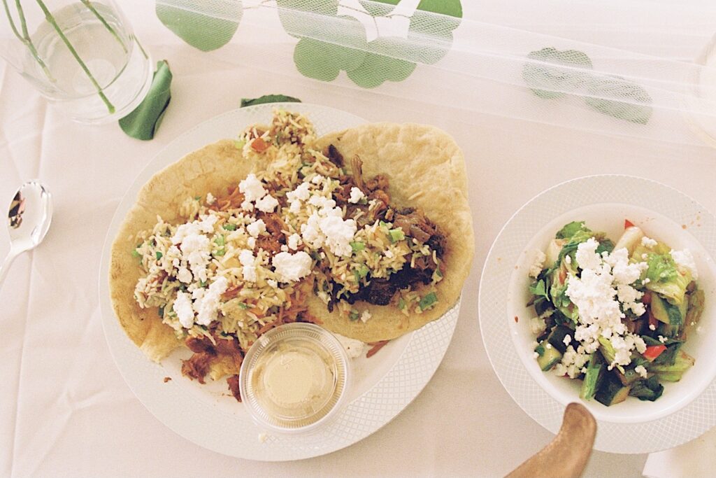 Film photo of tacos on a plate next to a plate of salad on a table