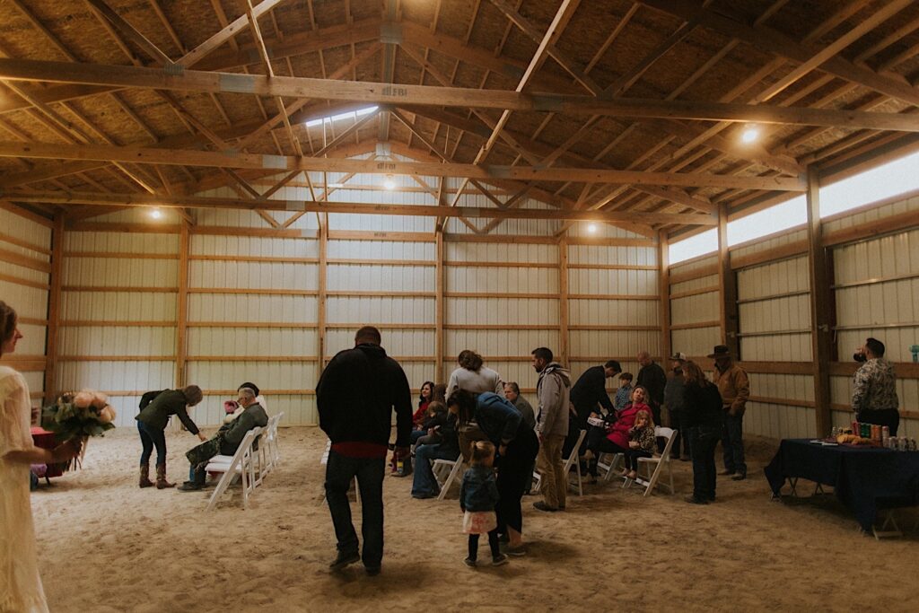Guests are seated in a barn for a wedding ceremony
