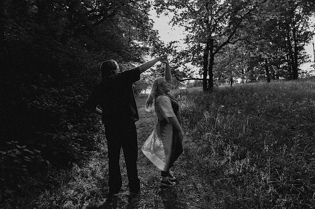 Black and white photo of a couple dancing on a walking path in a park near downtown Springfield during their engagement session