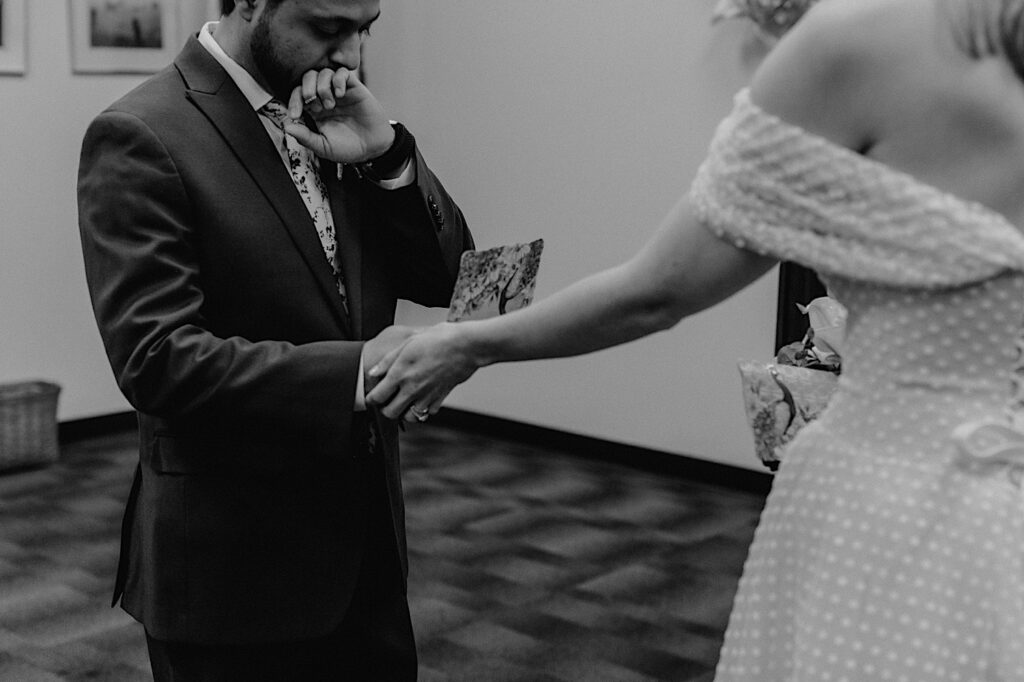 Black and white photo of a groom reading his vows to the bride as she holds his hand during their elopement at Sangamon County Courthouse