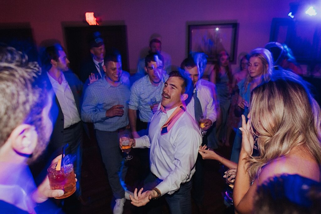 A groomsman dances in a dance circle at an indoor wedding reception at the Bloomington Country Club