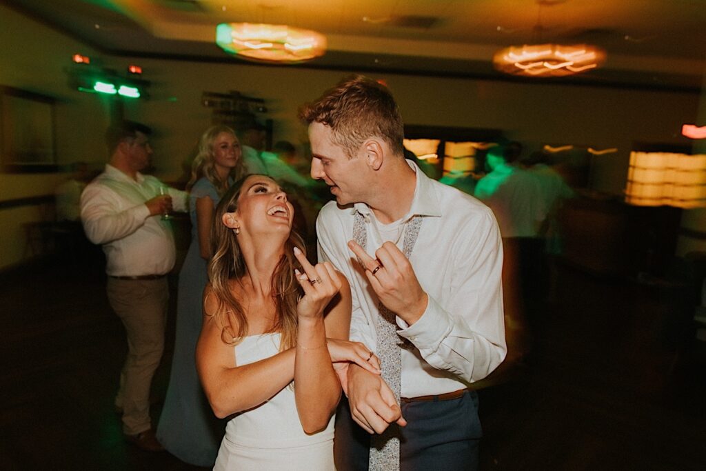 A bride and groom smile at one another on the dancefloor of their indoor wedding reception at the Bloomington Country Club