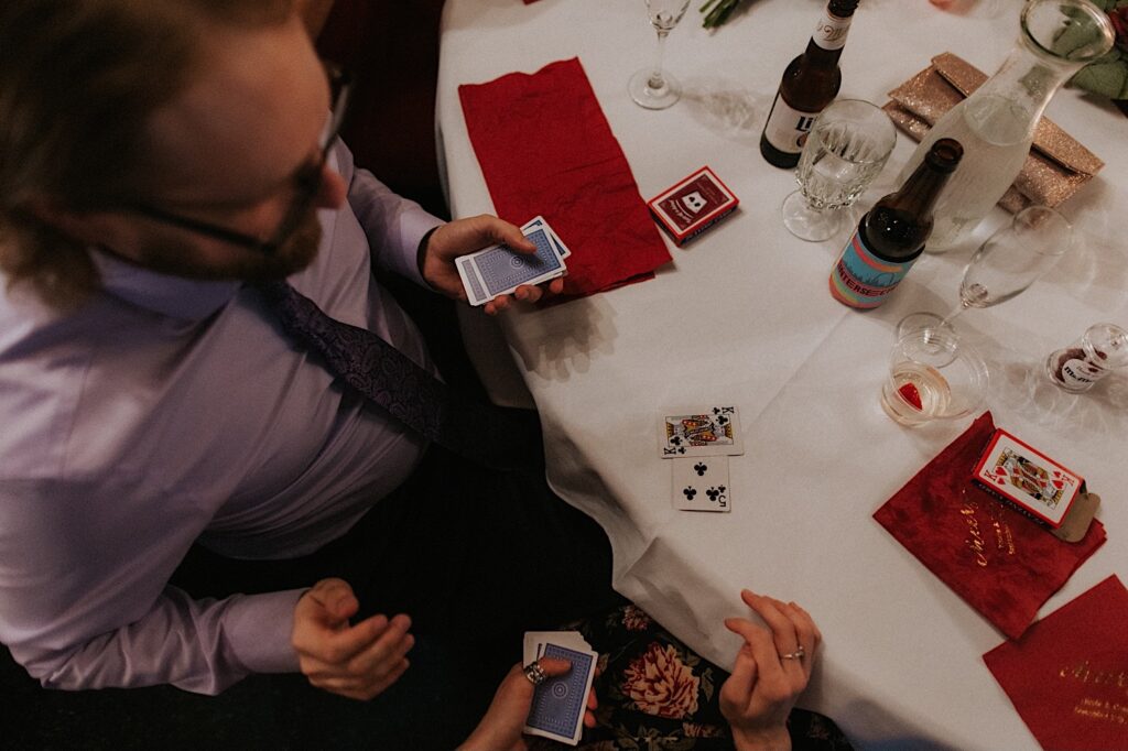 Top down photo of a guest at a wedding holding a deck of cards and playing a game with another guest at a table