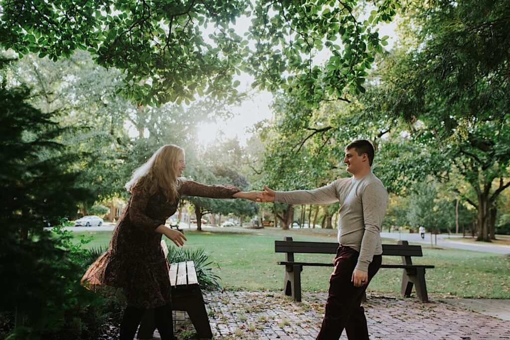 A couple in a park smile at one another while they dance during their engagement session in Springfield, Illinois
