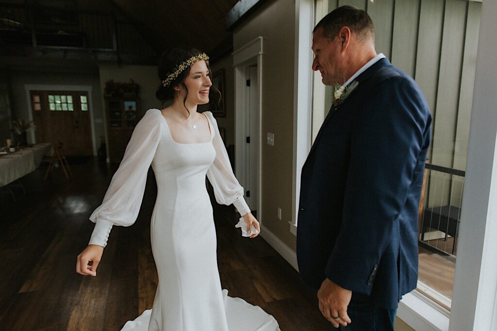 A bride smiles at her father as he tears up for the first time seeing her in her wedding dress before her intimate destination wedding in Tennessee