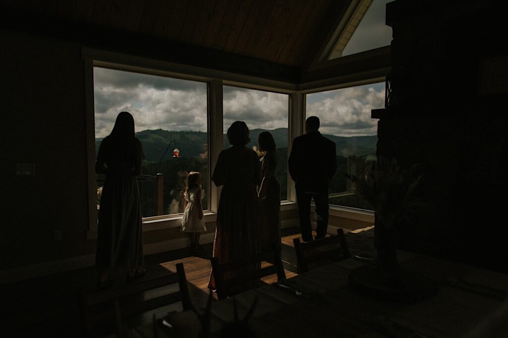 Guests of an intimate destination wedding in Tennessee stand and look out of a window towards the mountains in the distance