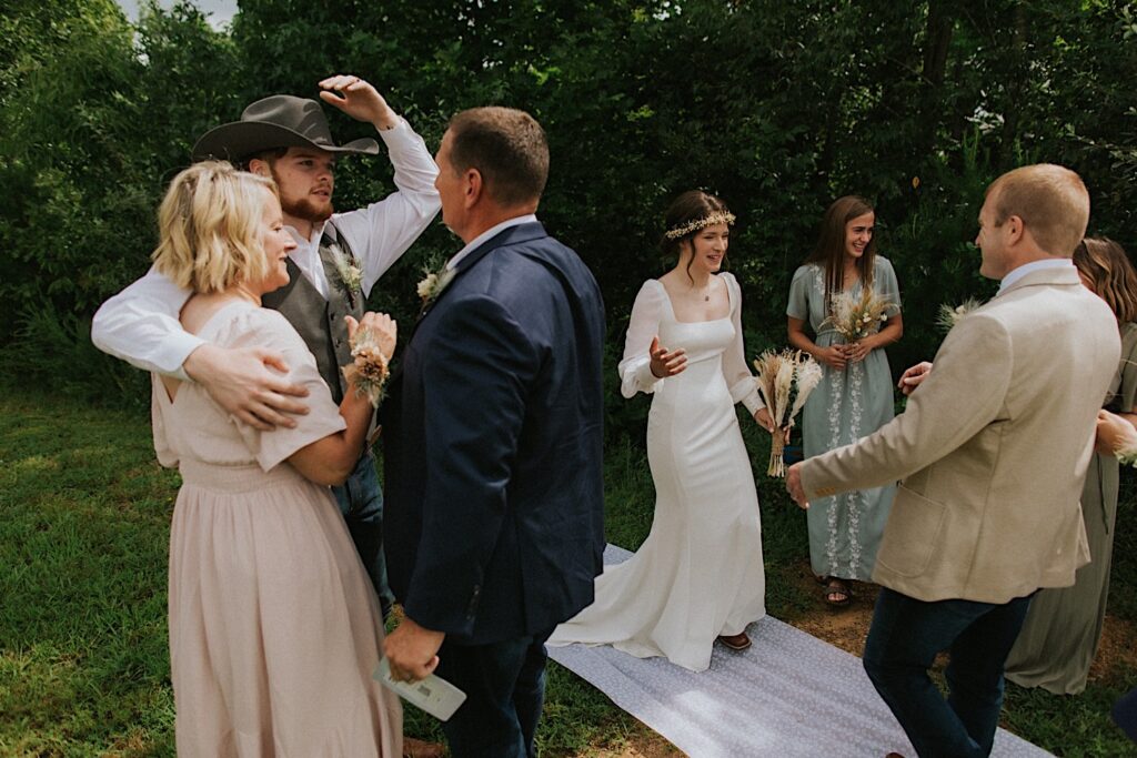 A bride and groom talk with and hug their parents after the ceremony of their intimate destination wedding in Tennessee