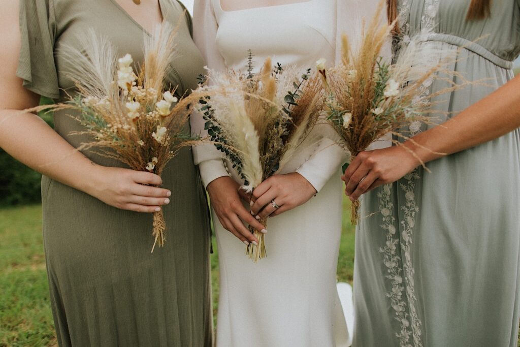 Detail photo of a bride and two bridesmaids holding their bouquets in front of them