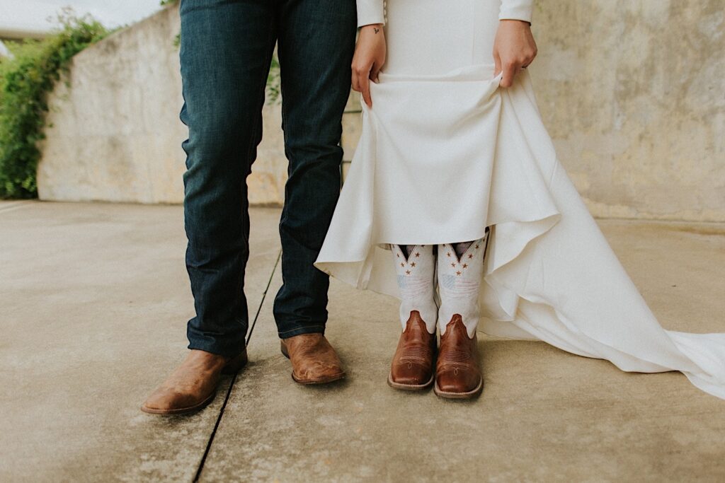 Waist down photo of a bride and groom showing off the boots they're wearing for their intimate destination wedding in Tennessee, the bride is lifting her dress so the boots are visible