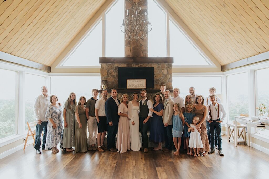 A bride and groom stand with the guests of their wedding around them, they're all standing in front of a fireplace after their intimate destination wedding in Tennessee