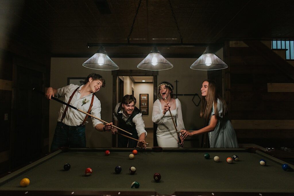 A bride and groom play pool with two of the members of their wedding part with them after their intimate destination wedding in Tennessee