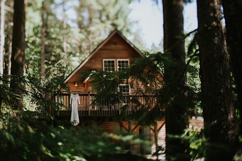 Photo of an Airbnb in the woods with a wedding dress hanging from the 2nd floor deck railing