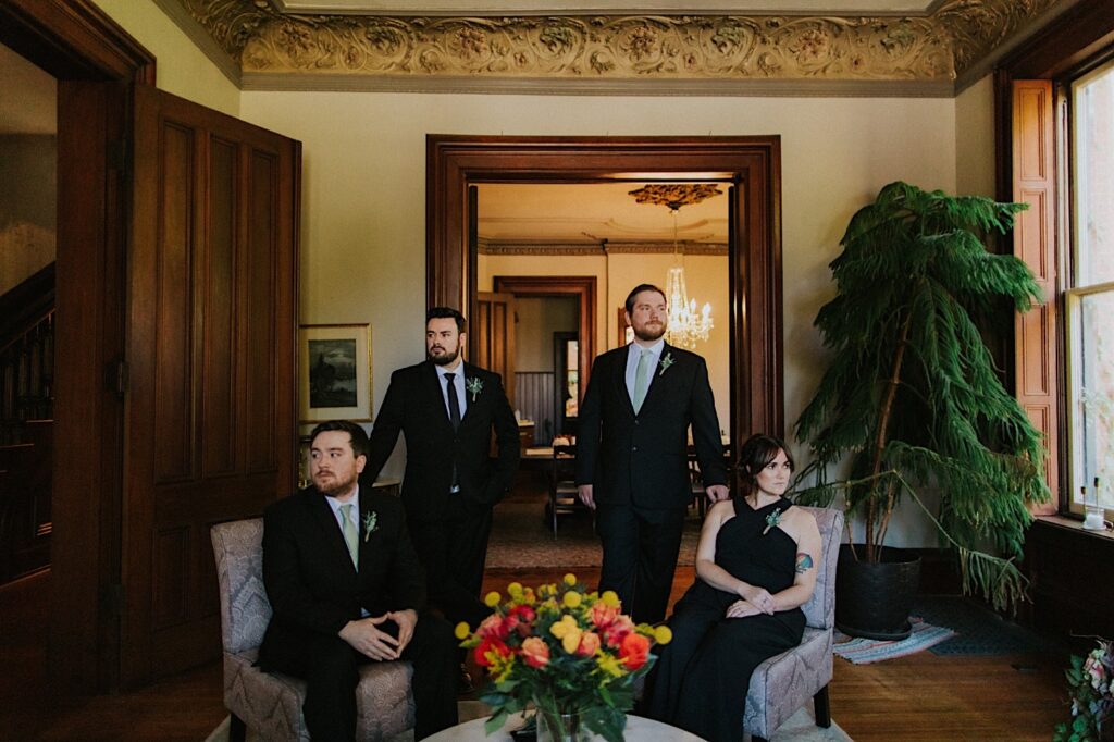 A groom and 3 guests of his elopement sit and pose inside of an Airbnb prior to the elopement ceremony taking place