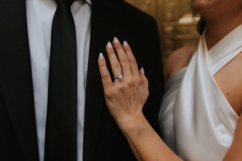 Close up photo of a woman's hand with an engagement ring resting on the chest of a man during their engagement session in Chicago