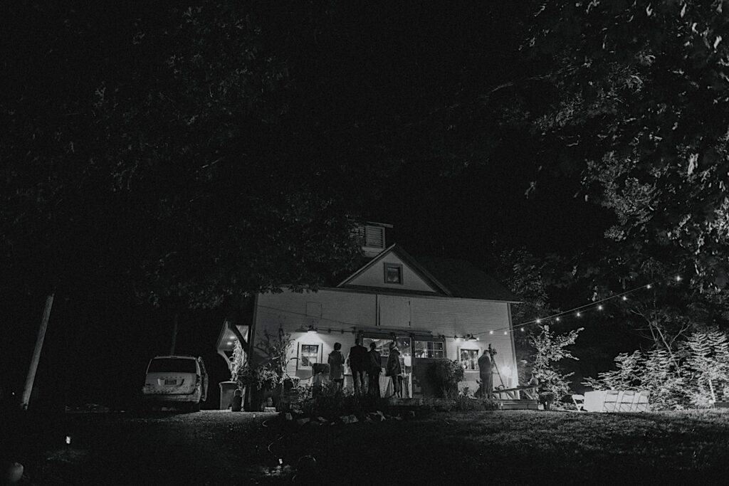 Black and white photo of guests of an elopement mingling outside of an Airbnb