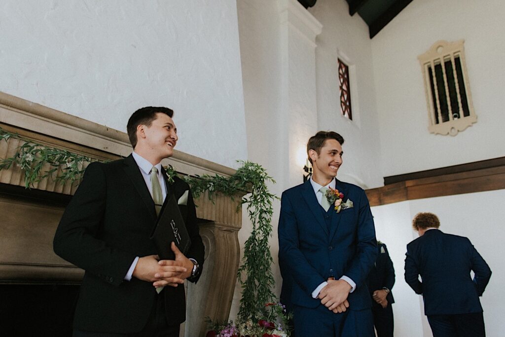 A groom smiles alongside his officiant while inside the wedding ceremony space of Venue 1929 in Springfield
