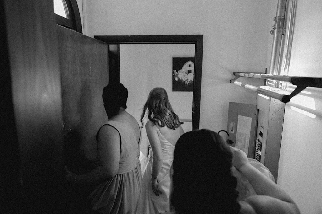 Black and white photo of a bride sneaking away to a different room to put on her 2nd wedding dress