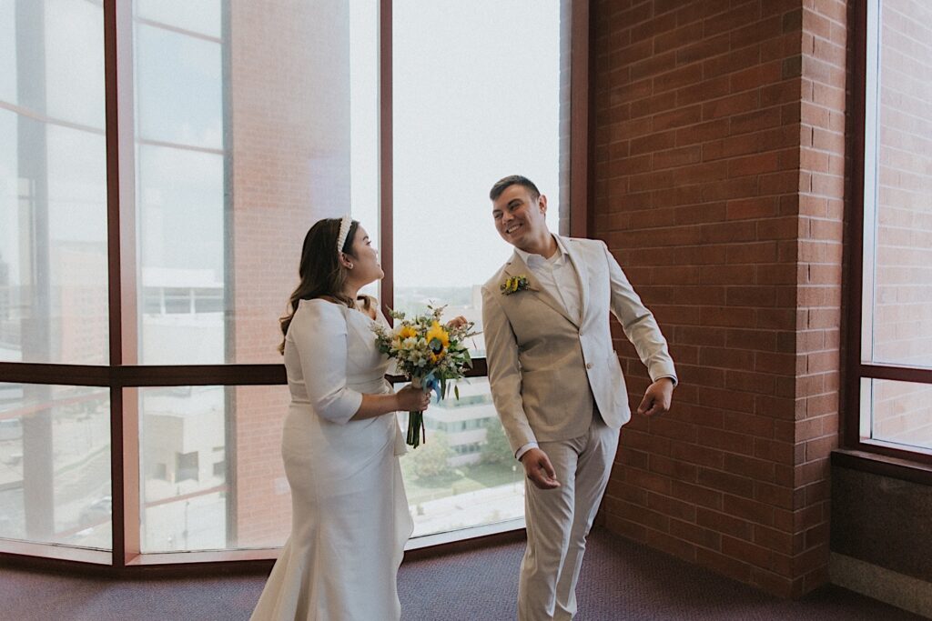 A groom smiles as he turns around to see the bride for the first time in her wedding dress before their wedding at the Sangamon County Courthouse