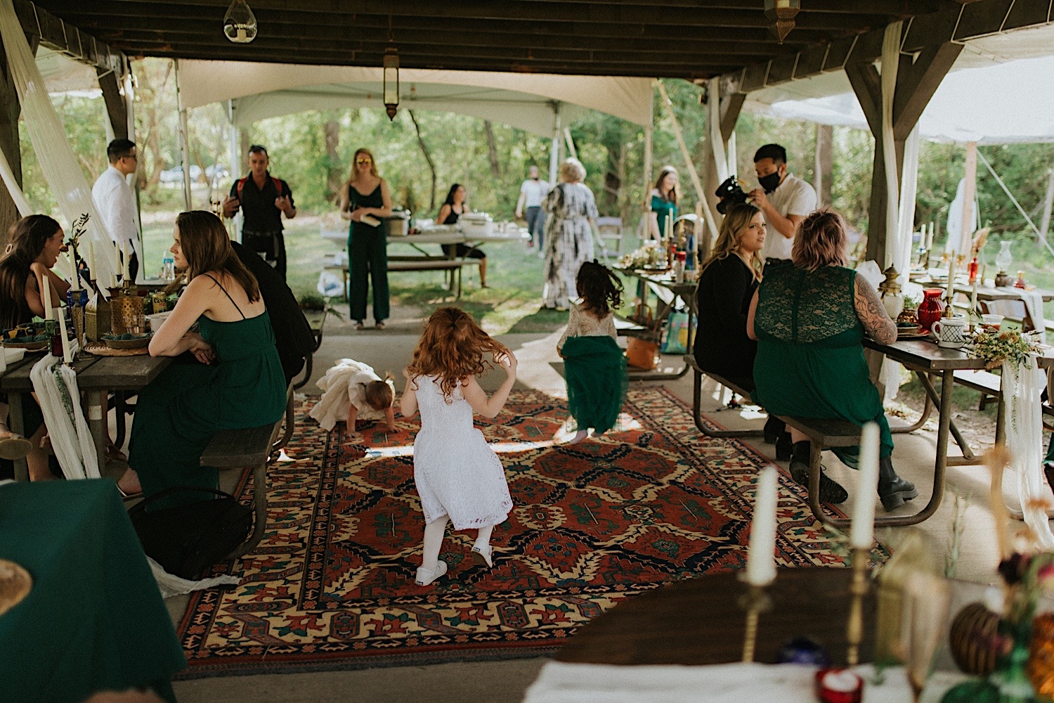 Children dance together while under a tent during an outdoor wedding reception