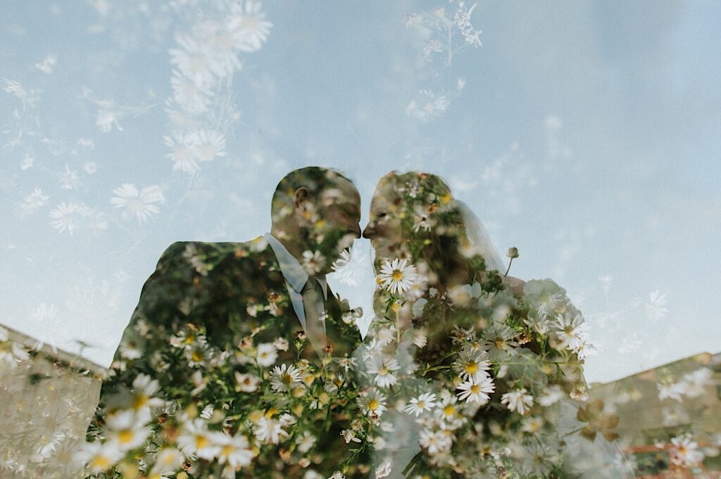 A bride and groom smile as they're about to kiss, overlaid on the photo is a photo of white and yellow flowers