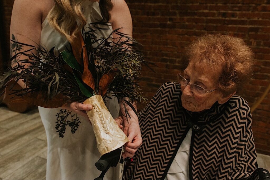 A bride shows her bouquet to her grandmother after her intimate wedding ceremony at Reality on Monroe