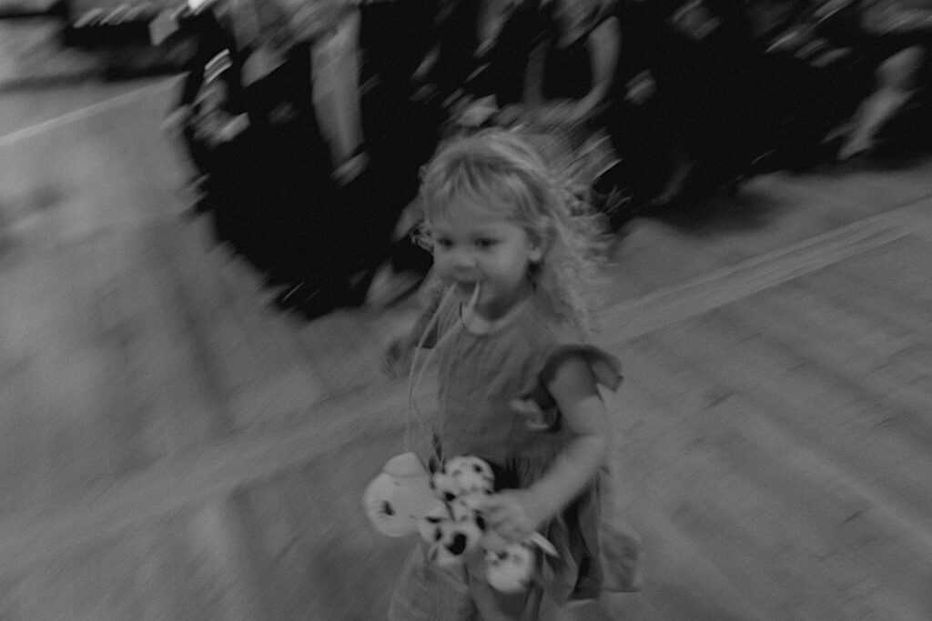Black and white photo of a flower girl running down the aisle of a wedding ceremony at Trailside Event Center