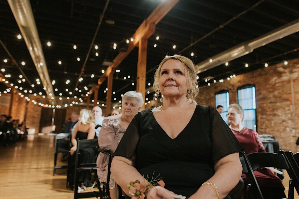 The mother of a bride sits with other guests of a wedding ceremony at Trailside Event Center