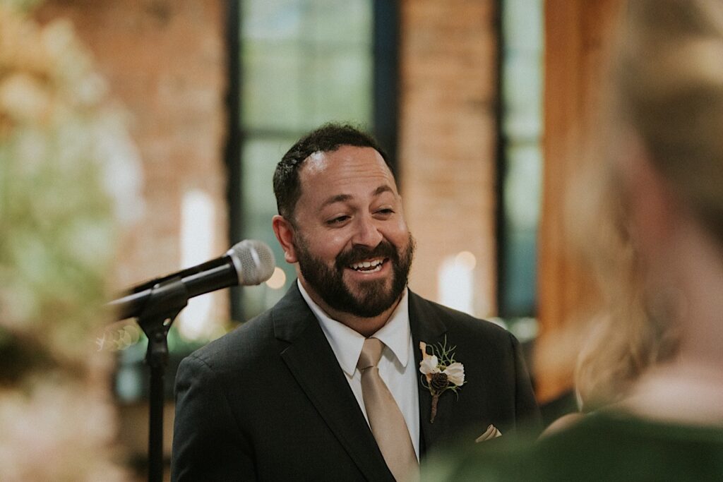 A groom smiles during his wedding ceremony inside of Trailside Event Center