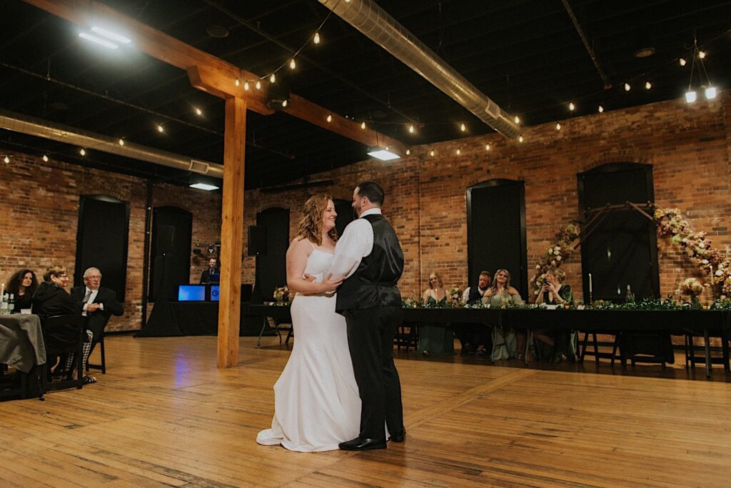 A bride and groom share their first dance together as guests watch during their wedding reception at Trailside Event Center