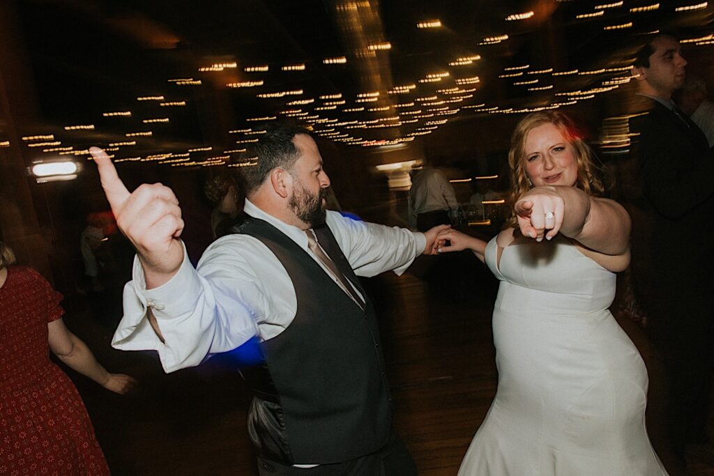 A bride and groom dance together as the bride points at the camera during a wedding reception at Trailside Event Center