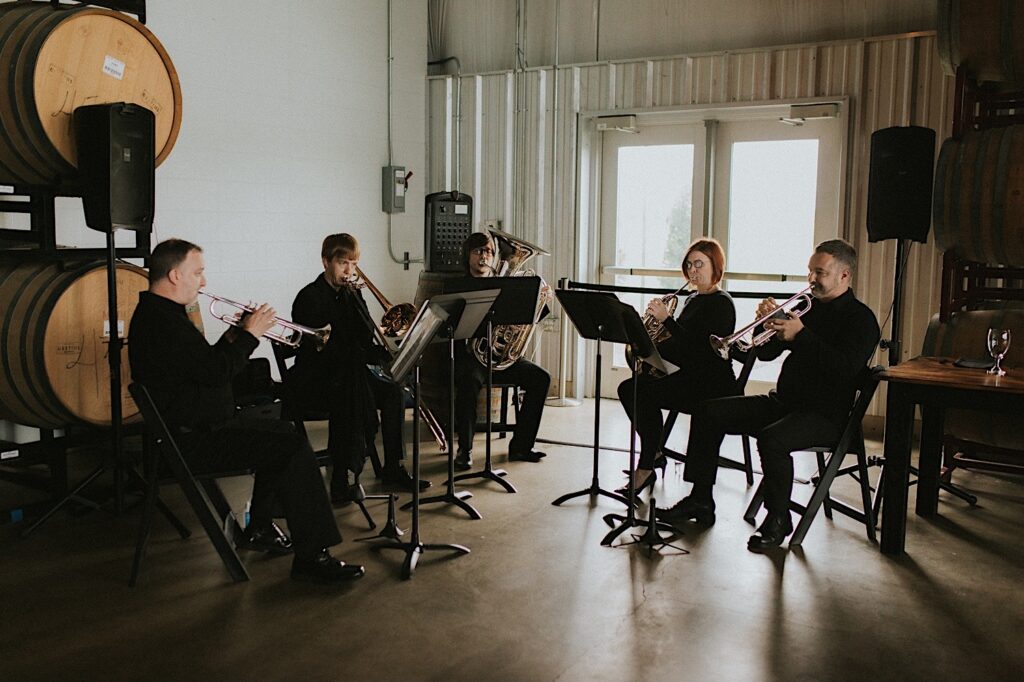 A 5 piece horn band play music during a wedding ceremony at the venue, The Barrel Room of the Destihl Brewery in Central Illinois