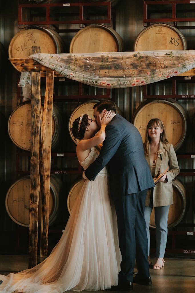 A bride and groom kiss during their wedding ceremony at The Barrel Room of the Destihl Brewery