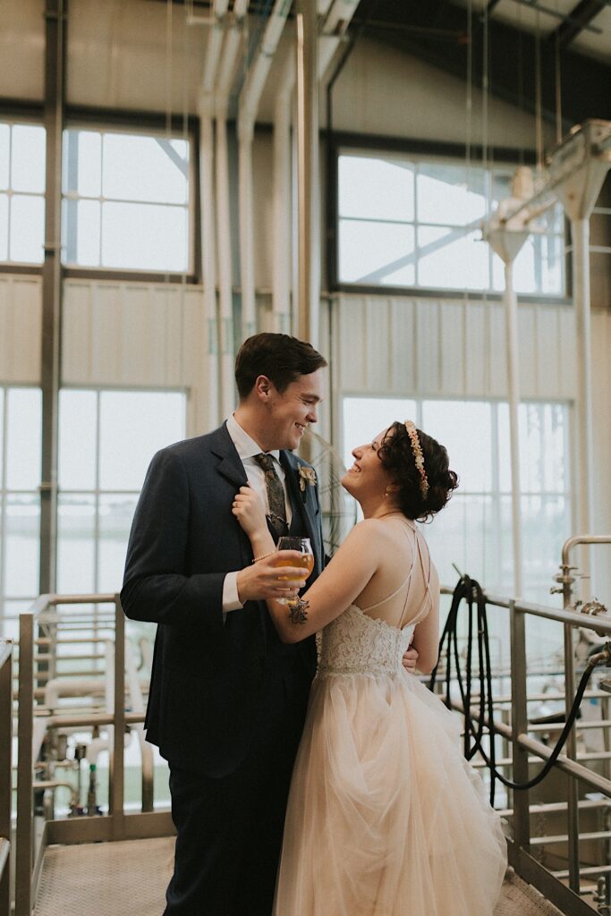 A bride and groom smile at one another while on a tour of the Destihl Brewery together