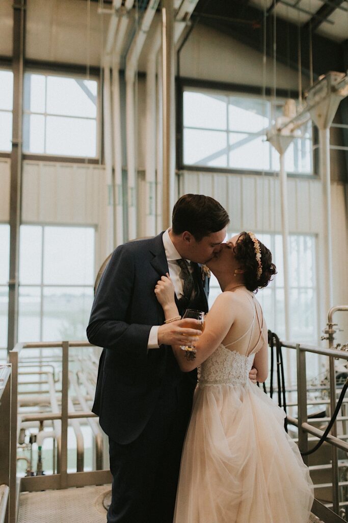 A bride and groom kiss one another while on a tour of the Destihl Brewery together