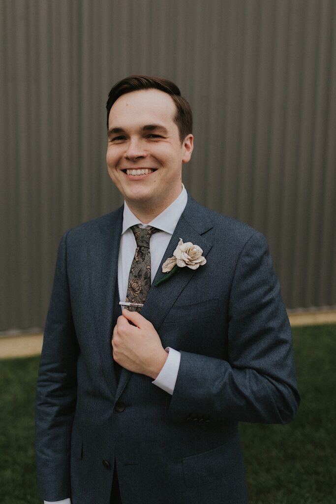 Portrait photo of a groom smiling while standing outside of a metal building