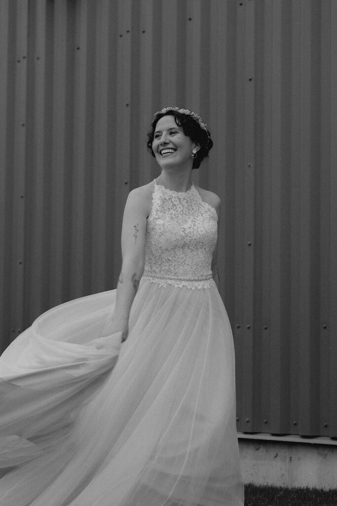 Black and white portrait photo of a bride smiling while outside of a metal building