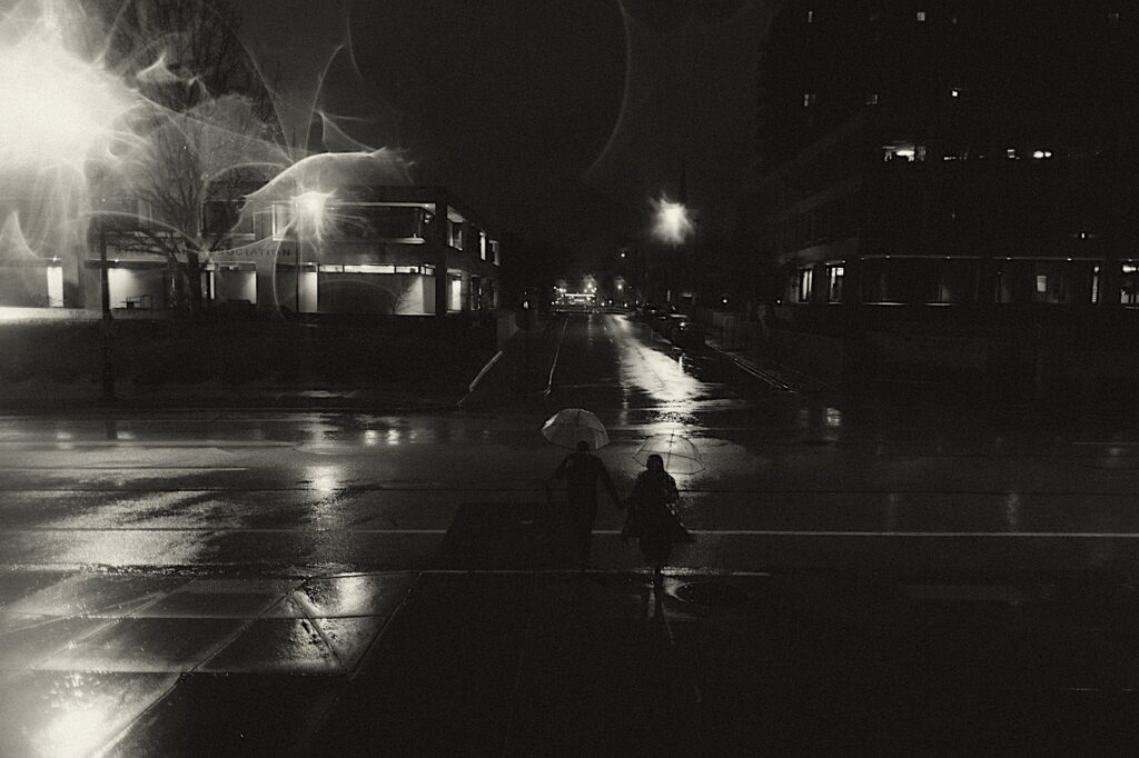 Couple running down the street in downtown Springfield, Illinois at night in the rain. 
