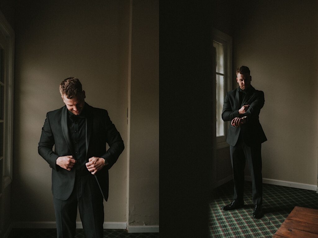 Groomsmen poses in moody lit room in all black suit. 