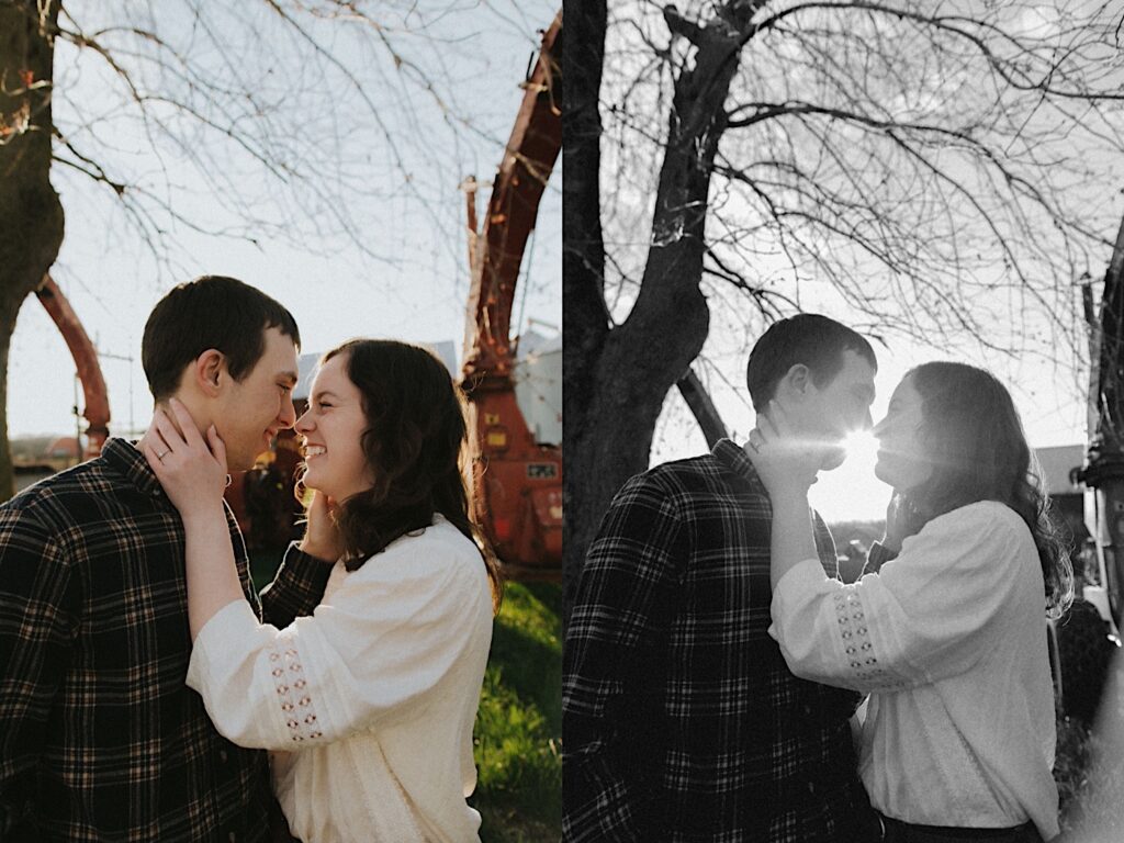 Couple holds each other's face with sunlight peeking through with farm background in central illinois 