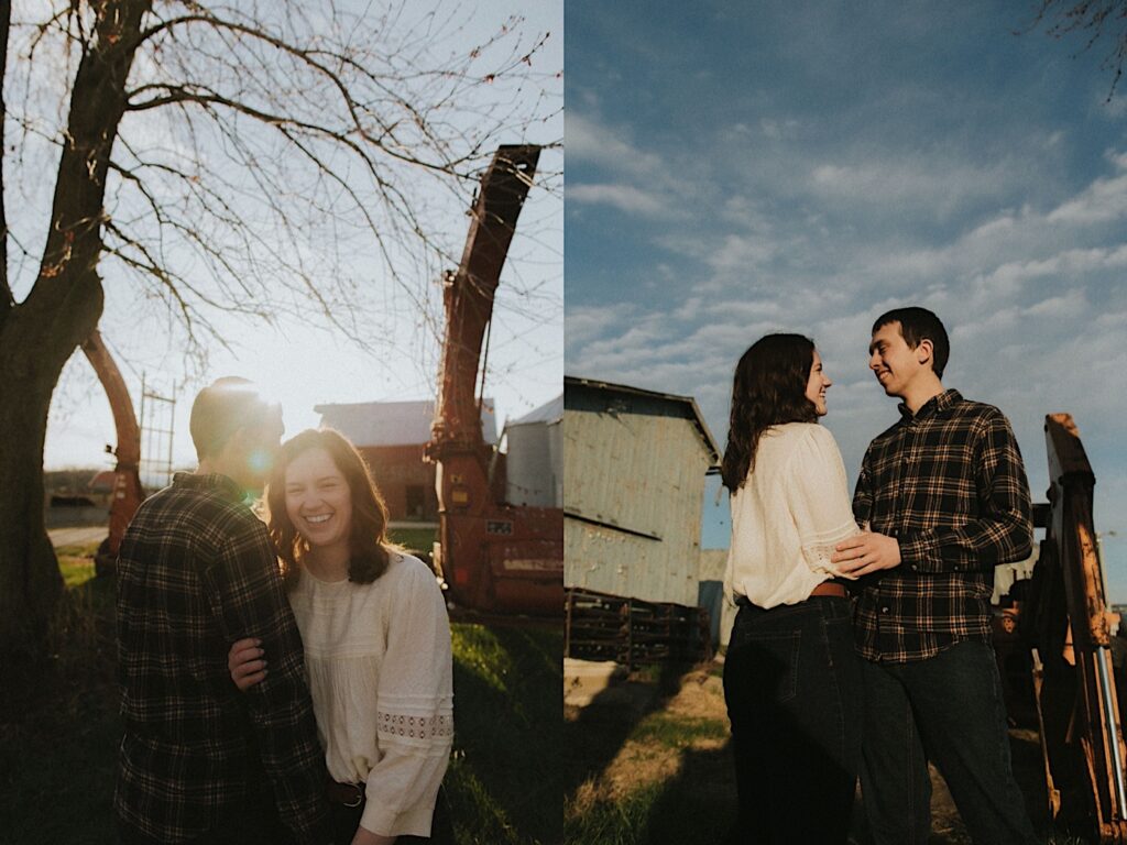 Couple stands next to a wood fence  for farm engagement photoshoot with a beautiful blue sky behind them. 